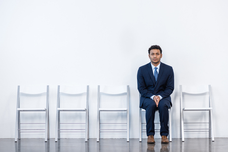 businessman in suit sitting on chair at white waiting roomの写真素材
