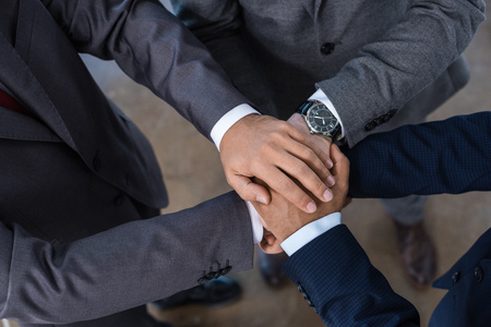 Close-up partial view of businesspeople in formal wear stacking hands togetherの写真素材