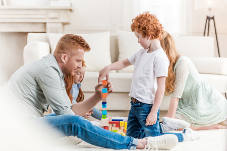 beautiful redhead family playing with constructor on floor at homeの写真素材