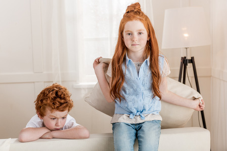 adorable redhead sister and brother sitting together on sofaの写真素材