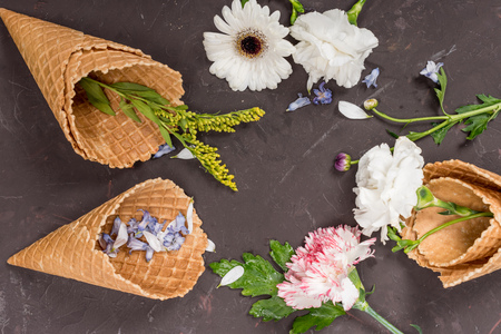 Close-up view of beautiful blossom flowers and petals in wafer cones on blackの写真素材