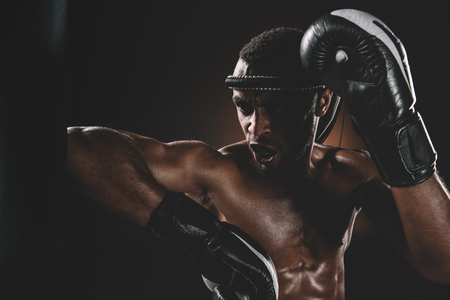 Aggressive young Muay Thai fighter in boxing gloves training thai boxingの写真素材