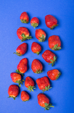 top view of heap of fresh red strawberries isolated on blue, berries top view conceptの写真素材