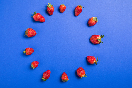 top view of fresh red strawberries in circle isolated on blue, berries background concept