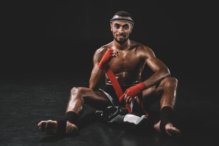 muay thai fighter swathing hand in bandage isolated on blackの写真素材