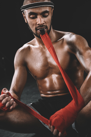 portrait of muay thai fighter swathing hand in boxing bandageの写真素材