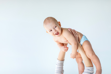 side view of mother holding adorable baby boy above the head isolated on grayの写真素材