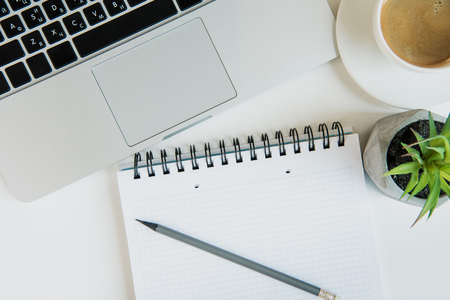 Top view of laptop with office supplies and cup of coffee on table topの写真素材