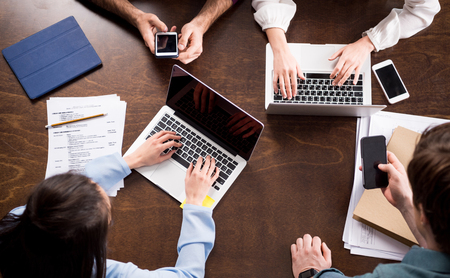 young businesspeople sitting together at workplace and using digital devices