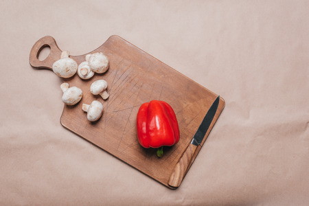top view of bell pepper and mushrooms with knife laying on wooden boardの写真素材