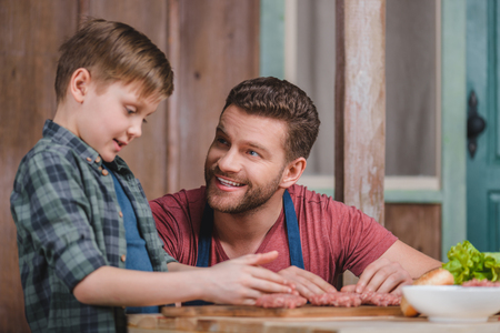 Happy father and son cooking meat patties togetherの写真素材