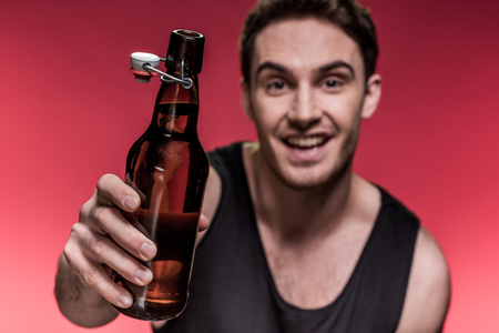 smiling young man holding beer bottleの写真素材