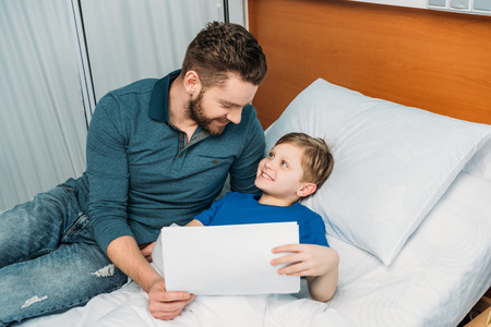 Father and son drawing together in hospital chamberの写真素材