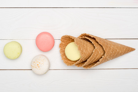 Top view of colorful macaroons in waffle cones on wooden surface. macarons backgroundの写真素材