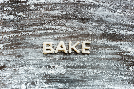 top view of word bake made from cookie dough with flour on wooden surfaceの写真素材