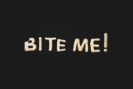 top view of lettering bite me made from cookie dough isolated on blackの写真素材