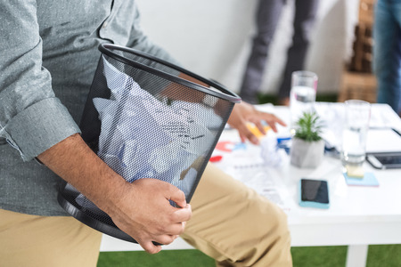 businessman holding trash bucket with papersの写真素材