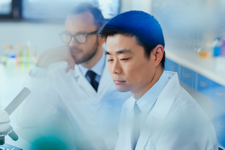scientists in white coats working together in chemical laboratoryの写真素材