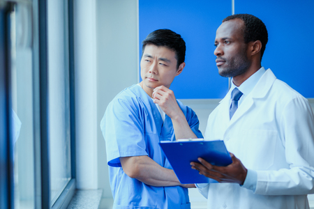 multiracial group of doctors in medical uniforms with folder in clinicの写真素材