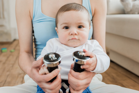 woman and baby boy playing with dumbbells at home