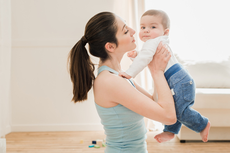 mother able to kiss her son at home in sunny dayの写真素材