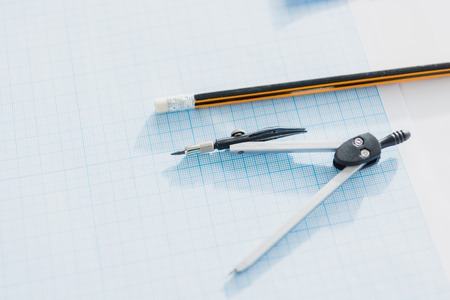close up of office compasses and pencil lying on empty blueprint