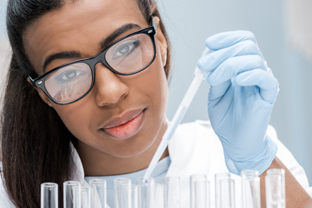 young scientist in eyeglasses working with test tubes in chemical lab