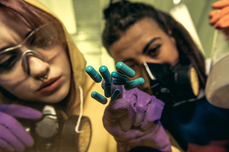 two young women chemists working at scientific laboratory with drugsの写真素材