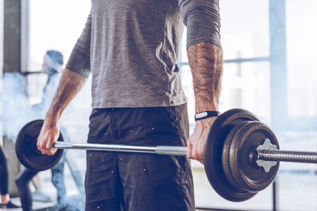 muscular sportsman lifting barbell at gym workoutの写真素材