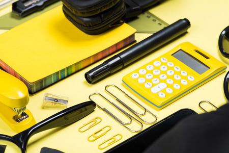 Close-up view of headphones, calculator and various school supplies on yellow