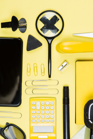 Close-up view of calculator, smartphone and school supplies on yellow