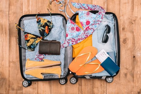Top view of open luggage full of woman's clothes and other essential vacation items. Ready to summer vacationの写真素材