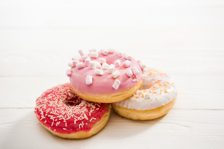 Close Up view of three tasty donuts with frosting on the top lying on wooden table. appetizing chocolate donuts backgroundの写真素材