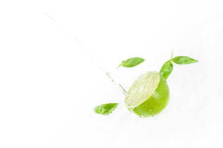 half of lime with green leaves and water drops isolated on white, fresh fruits backgroundの写真素材