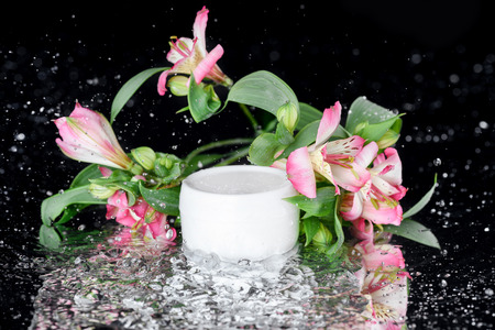 face cream in plastic jar with flowers in water, natural cosmetic conceptの写真素材