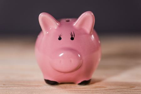 Close-up view of pink ceramic piggy bank on wooden table top, piggy bank savings conceptの写真素材