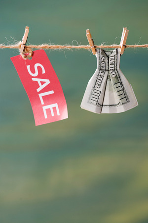 sale sign and one hundred us dollar banknote on clothesline, offer sale conceptの写真素材