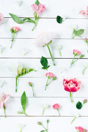 Top view of beautiful blooming flowers with green leaves on wooden tableの写真素材