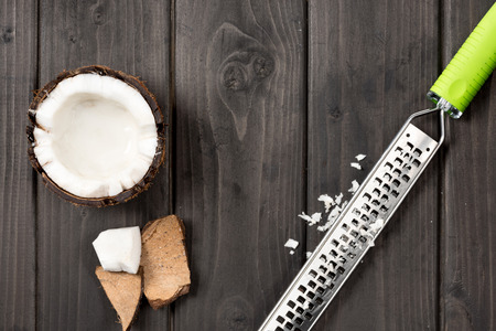 top view of coconut pieces with grater on wooden background, coconut shavingsの写真素材