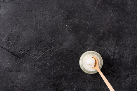 Top view of coconut oil in glass jar with spoon on black backgroundの写真素材