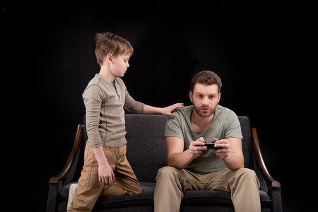Boy trying to talk with father playing with joystickの写真素材