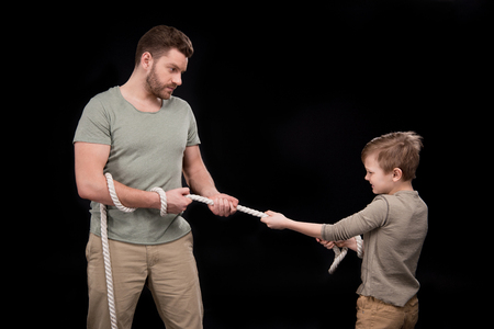 Father and son pulling rope isolated on blackの写真素材