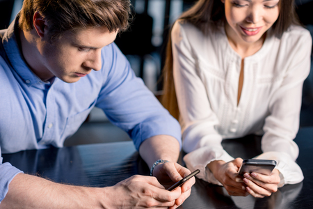 couple sitting together at table and using smartphones, lunch meeting conceptの写真素材