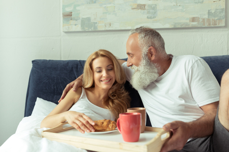 happy mature couple having breakfast in bedの写真素材