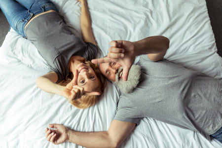 middle aged couple lying in bed and smilingの写真素材