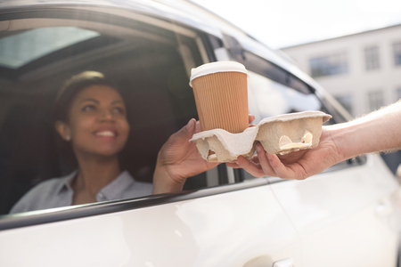 woman sitting in car and buying coffee to goの写真素材