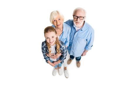 overhead view of happy grandfather, grandmother and grandchild hugging and looking at cameraの写真素材