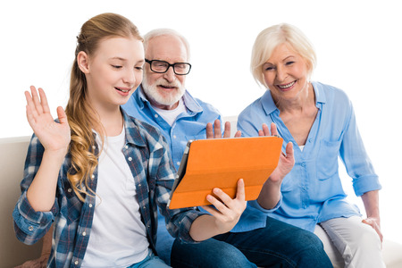 grandfather, grandmother and grandchild using digital tablet and sitting on sofaの写真素材