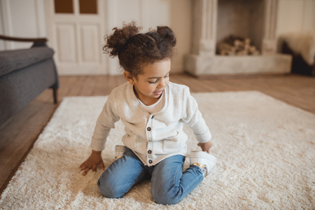 little african american girl sitting on carpet at homeの写真素材