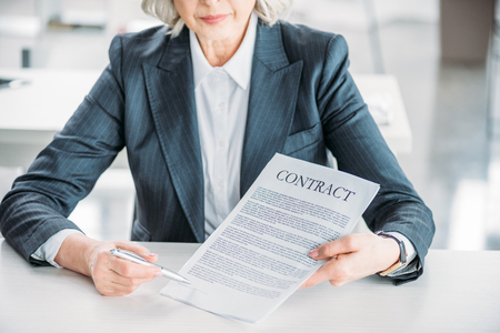 businesswoman sitting at workplace and pointing at contractの写真素材